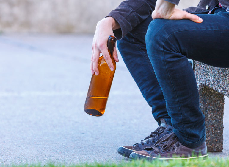 Chłopak trzymający butelkę z alkoholem